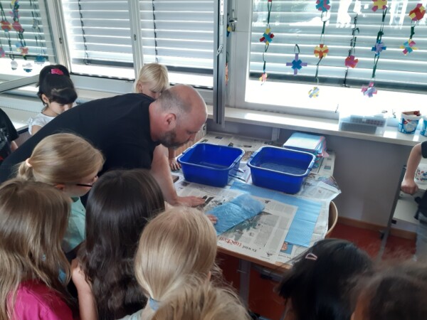 Timo Leischner zeigt den Kindern ein gepacktes "Papier-Päckchen".