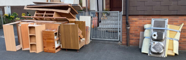 Das Bild zeigt einen Stapel Holzsperrmüll, daneben liegt der Restsperrmüll.