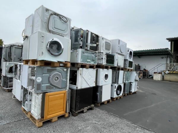 Das Bild zeigt aufeinandergestapelte Waschmaschinen auf dem Recyclinghof.